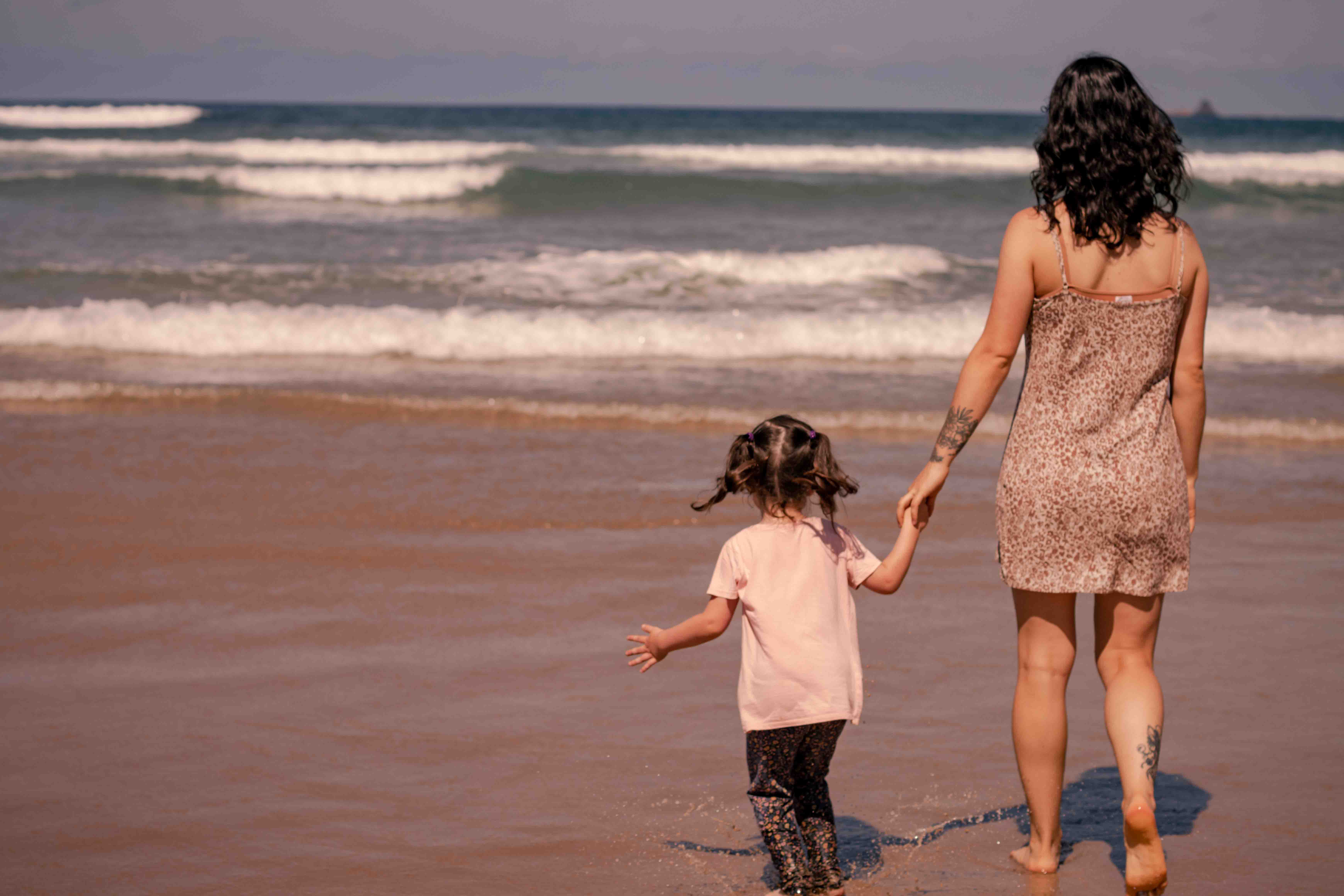 Courtney with her daughter walking on the beach